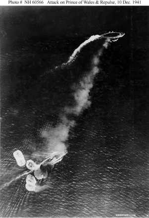 Loss of HMS Prince of Wales and HMS Repulse, 10 December 1941: Photograph taken from a Japanese aircraft during the initial high-level bombing attack. The battlecruiser Repulse, near the bottom of the view, has just been hit by one bomb and near-missed by several more. The battleship Prince of Wales is near the top of the image, generating a considerable amount of smoke. The Japanese writing in the lower right states that the photograph was reproduced by authorization of the Navy Ministry.