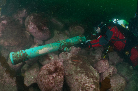 Een duiker bij een gezonken kanon