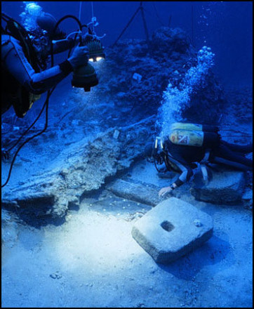 Divers at the bow of the wreck with a stone anchor