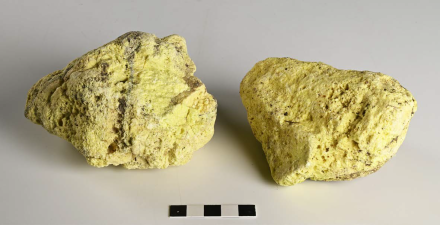 Twee gele steenachtige brokken van zwavel met een witte achtergrond.