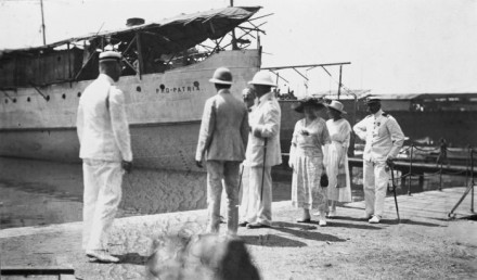 A group of men in white colonial uniforms with the Pro Patria in the background.