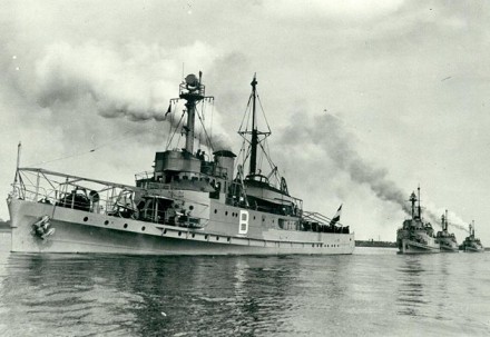 A black and white photo of four minesweepers sailing in one line.