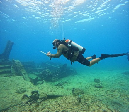 An underwater photo of a person taking notes underwater.