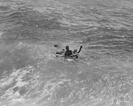 A black and white photo of two people in the sea.