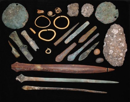 A photo of a number of artefacts such as tools and jewellery on a black background.